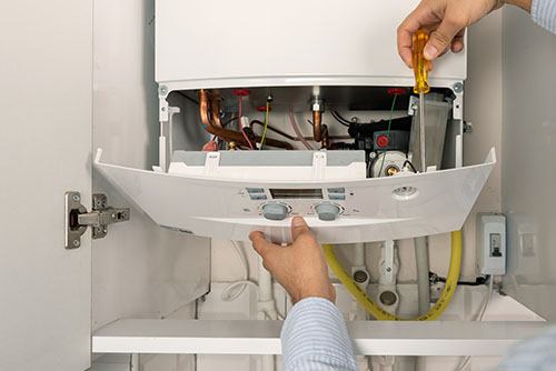 Heating technician repairing a residential boiler in Belmont