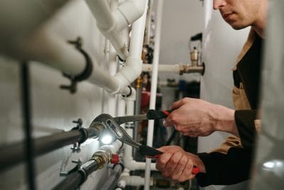 Technician inspecting commercial plumbing pipes in Belmont