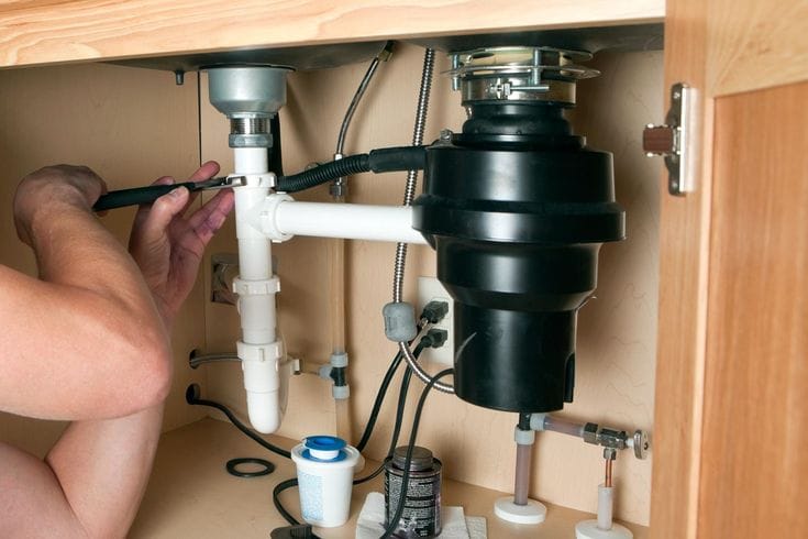 Plumber repairing a garbage disposal in Belmont