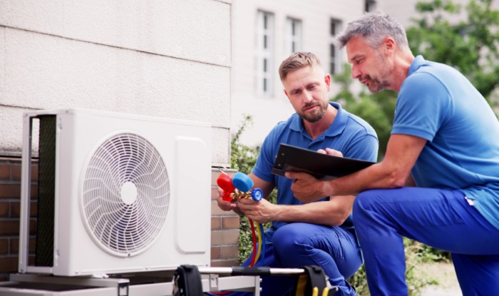 HVAC technicians installing an outdoor air conditioning unit in Belmont