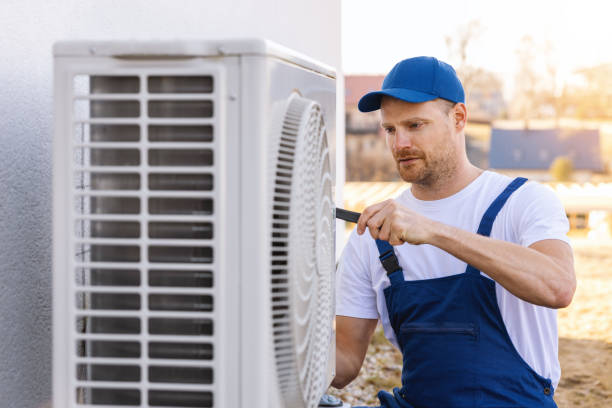 HVAC technician servicing an outdoor air conditioner in Belmont