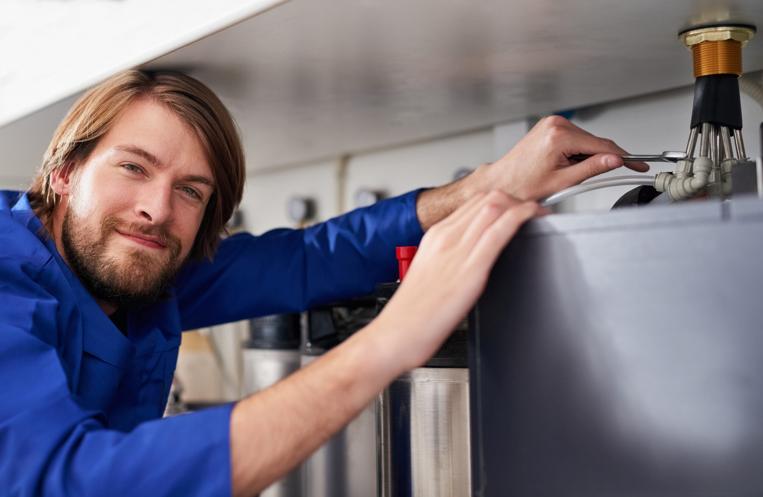 Technician servicing a residential water heater tank in Belmont